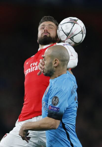 Olivier Giroud del Arsenal (detrás) pelea con el balón junto con Mascherano del Barcelona.