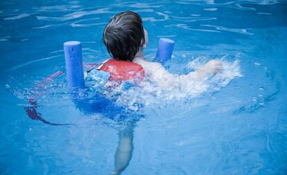 Un niño nada en una piscina. 