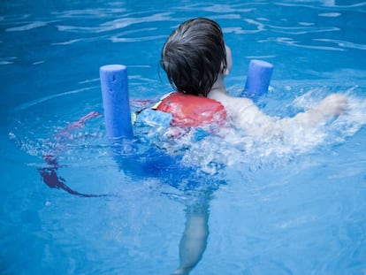 Un niño nada en una piscina.