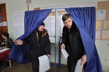 Dos civiles rusos salen de una cabina electoral de la localidad rusa de  Krivskoe.