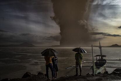 Tres personas observan el volcán Taal en erupción, el 12 de enero, en Talisay (Filipinas).