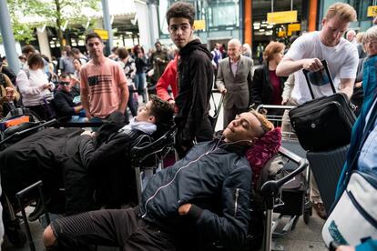 Dos jóvenes se tumban sobre sus equipajes mientras hacen cola fuera de la Terminal 5 del aeropuerto de Heathrow, en Londres, Reino Unido.