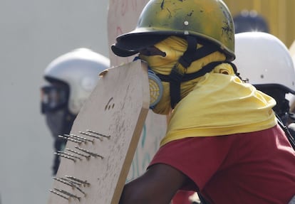 Un opositor del gobierno de Venezuela sujeta un escudo con clavos en las protestas de Caracas contra el presidente Maduro, en Venezuela.