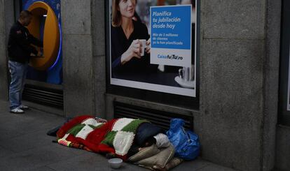 Un mendigo duerme junto a una entidad bancaria en Madrid.