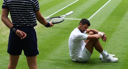 Un recogepelotas sujeta la raqueta de Djokovic tras una caída del tenista serbio. 