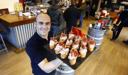 Un camarero sostiene una bandeja de pinchos en un local de Lizarran.