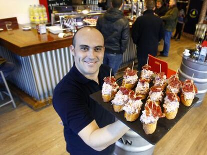 Un camarero sostiene una bandeja de pinchos en un local de Lizarran.