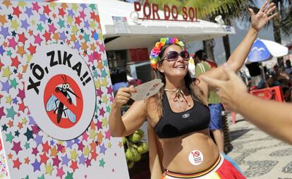 Uma gr&aacute;vida dan&ccedil;a ao lado de cartaz contra o zika no Carnaval do Rio.