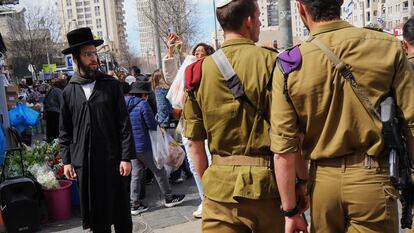 Militares pasan delante de un ultraortodoxo en una calle de Jerusalén este viernes