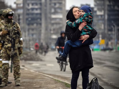 Una mujer sostiene y besa a un niño junto a soldados rusos en una calle de Mariupol el 12 de abril de 2022.