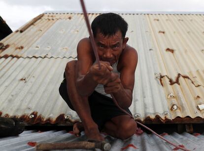 Un aldeano filipino asegura el techo de una casa en la ciudad de Aparri (Filipinas). 
