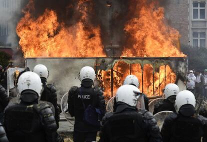 Agentes de policía junto a un coche ardiendo durante la manifestación de ganaderos 7 de septiembre de 2015 en Bruselas (Bélgica). La policía belga disparó cañones de agua a los agricultores europeos, mientras éstos exigían la intervención de la UE contra la caída de los precios de los alimentos, que atribuyen al embargo ruso.