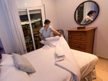 Una camarera de piso hace la cama de una habitación de hotel.
