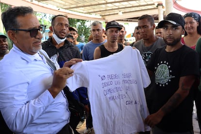 Migrantes sostienen una camiseta con el mensaje "No pueden seguir siendo las fronteras cementerio de migrantes", durante una vigilia, este martes, en Tapachula, (México).