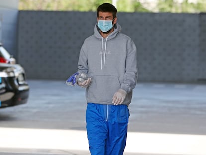 Pique accede a la ciudad deportiva del Barcelona con guantes, mascarilla y líquiros desinfectantes.