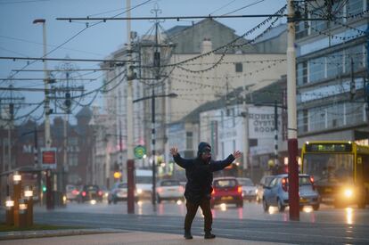 Un hombre lucha contra el viento en una calle de Blackpool, Inglaterra.