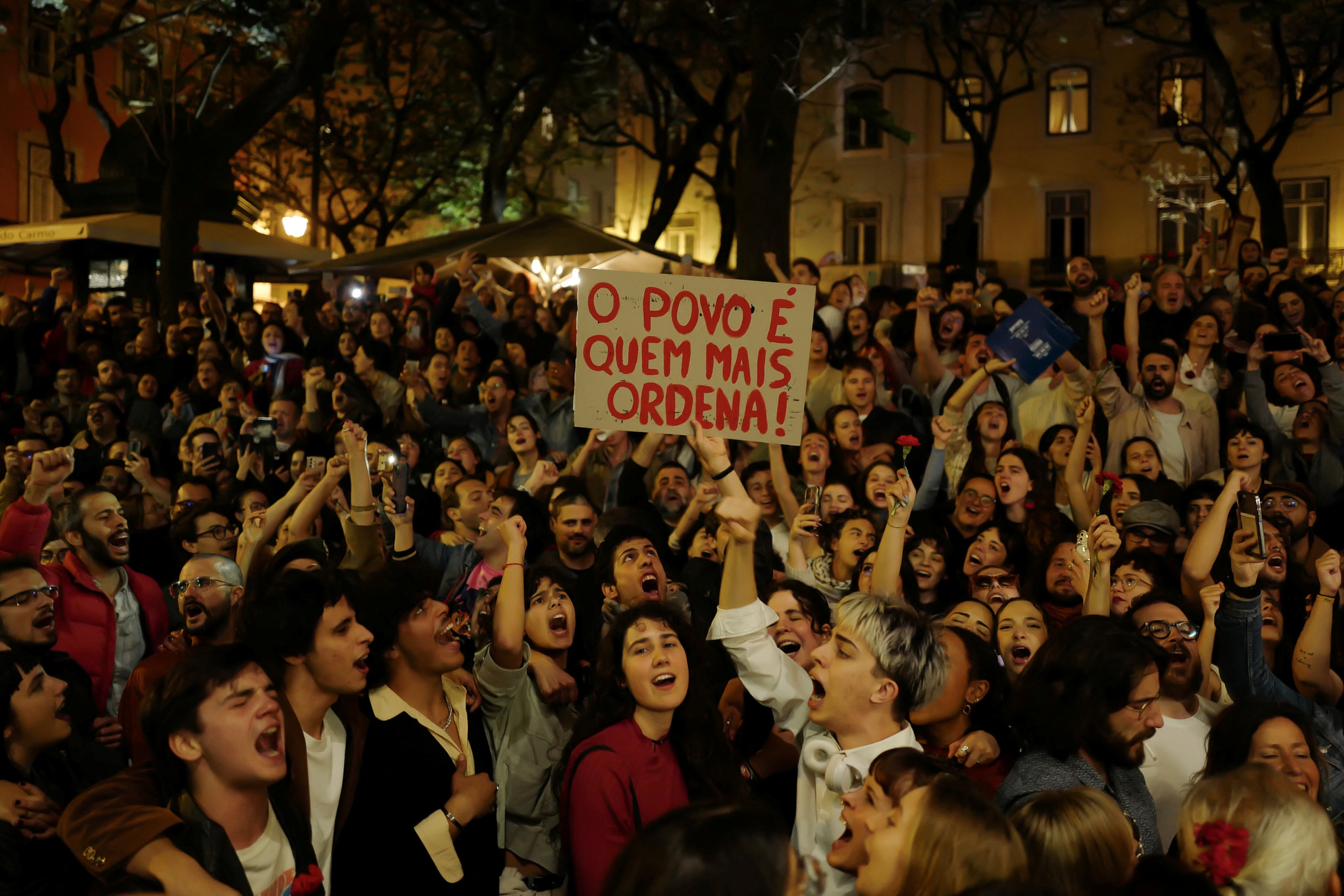 Centenares de personas cantan el himno de la revolución de abril,  'Grândola, vila morena', en el arranque de la fiesta de conmemoración, en Lisboa, el 24 de abril.