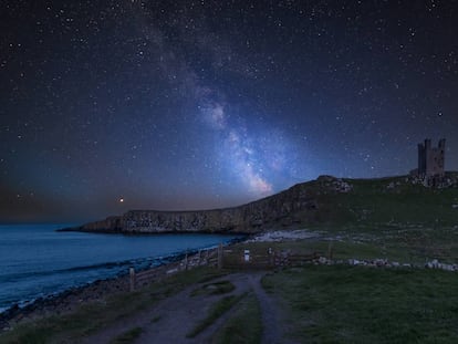 La Vía Láctea visible de noche cerca del castillo de Dunstanburgh Castle, en la costa de Northumberland (Inglaterra).