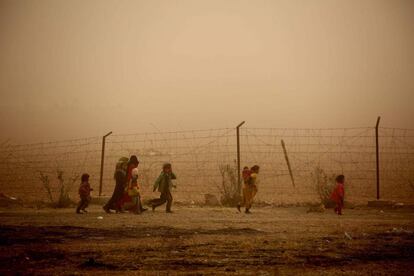 Niños sirios juegan en un campamento durante una tormenta de arena, en Ain Issa (Siria).