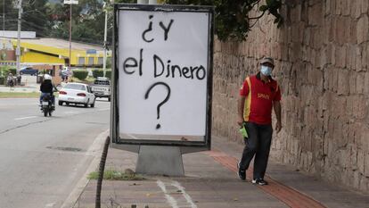 Un ciudadano hondureño camina frente a una pintada, alusiva a una pregunta sobre dónde está el dinero, durante la crisis sanitaria que se vive en el país debido al coronavirus, en Tegucigalpa (Honduras).