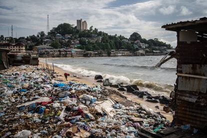 Un señor recoge objetos entre la basura de West Point. Al fondo, la colina que separa el 'slum' del centro de la ciudad. 