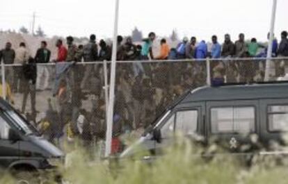 Inmigrantes subsaharianos que permanec&iacute;an encaramados a la valla de Melilla, tras protagonizar un intento de entrada masivo a la ciudad.