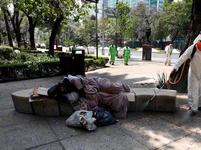 Un hombre duerme en un banco mientras un empleado del Gobierno desinfecta el área en Ciudad de México, el año pasado.