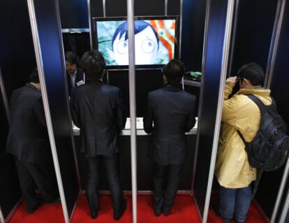Asistentes a la Feria Del Anime de Tokio ven con unas gafas especiales una animación en 3D en televisores.