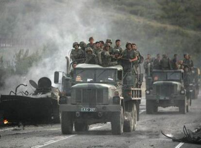 Un convoy del Ejército georgiano pasa junto a los restos de un carro de combate destruido por las fuerzas rusas, en Gori, en agosto de 2008.