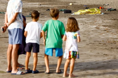 Varios niños observan las pertenencias de las personas que llegaron en cayuco esta mañana a la playa de Las Burras. 