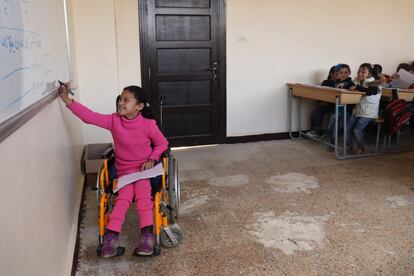 A pesar de haber perdido la movilidad de las piernas tras la explosión de una bomba, Hanaa, de ocho años, ha vuelto a los estudios tras una interrupción de un año. En esta imagen, resuelve un problema en su escuela en Alepo (Siria).