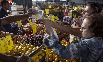 Dos mujeres pagan una bolsa de frutas en el Mercado Central de Buenos Aires