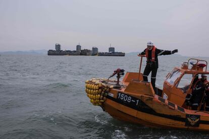 Un policía de un guardacostas realiza señales desde su barco durante la operación de remolque del ferri Sewol en las costas de Jindo (Corea del Sur).
