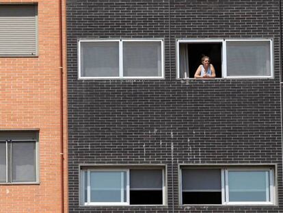 Una vecina se asoma a una ventana del edificio Memoria, de la EMVS, en la calle de Barrileros.