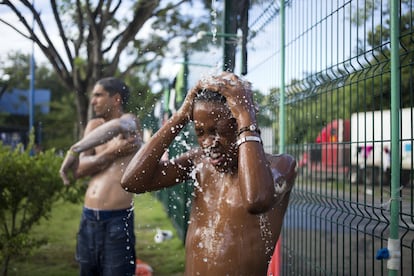 Eliel Becker, un inmigrante cubano, se baña en una ducha portátil, situada en el exterior de la oficina de inmigración de Peñas Blancas, en Costa Rica.