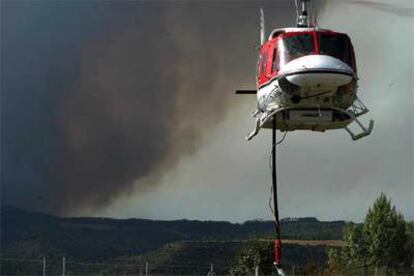 Un helicóptero arroja agua para sofocar el incendio en Cardona.