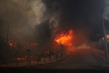 Un edificio de secundaria y su gimnasio se ven en llamas mientras arde un incendio forestal en Nea Penteli, el martes.