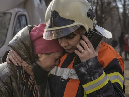 Una bombera consuela a otra mujer frente a un edificio de apartamentos destruido tras un ataque ruso en Kiev, este martes.