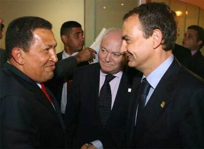 Chávez, a la izquierda, y Zapatero se estrechan la mano ante la mirada de Moratinos en la cumbre de Lima.