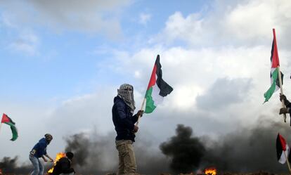 Un manifestante sujeta una bandera palestina durante los enfrentamientos contra las tropas israelíes en Gaza. 