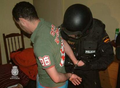Imagen facilitada por la policía en la que un agente esposa a uno de los detenidos.
