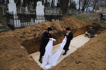 Dos rabinos colocan una tela blanca sobre la tumba de las 40 víctimas del Holocaustro en la fosa del cementerio de Iasi, a 410 kilómetros al norte de Bucarest.