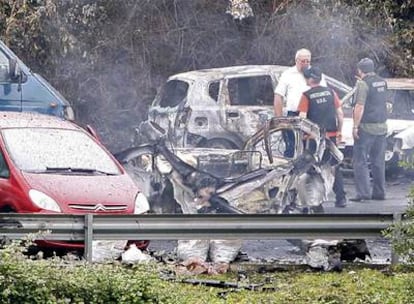 Agentes policiales junto a los restos del vehículo de Puelles y otros automóviles afectados por la explosión que le costó la vida al inspector antiterrorista.