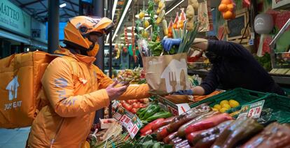 Un mensajero recoge la compra en un puesto de mercado.