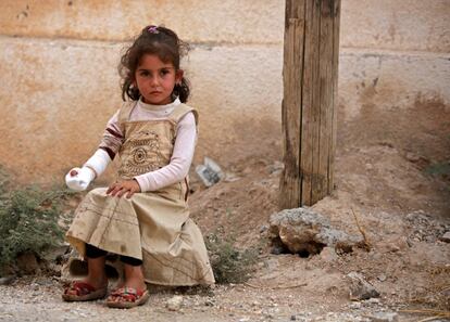Una niña siria sentada al lado de una carretera después de recibir tratamiento en la ciudad fronteriza siria de Tal Abyad.