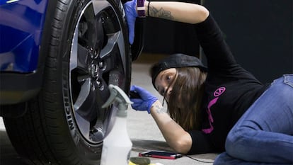 Una chica limpiando los frenos de su coche.