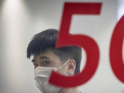 Un hombre se protege con una mascarilla en una tienda de Huawei en Shanghai. 