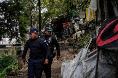 Policías municipales vigilan el área donde solía estar la casa que quedó bajo la tierra.