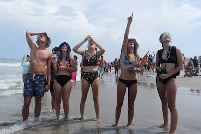 Un grupo de jóvenes observa desde la playa el lanzamiento de la nave 'Crew Dragon' desde Cabo Cañaveral.