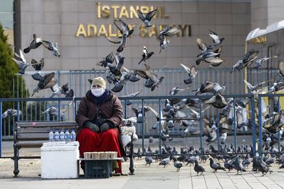 Una mujer que vende comida para los pájaros sentada fuera del tribunal donde se celebra el juicio contra activistas acusados por los cargos de pertenencia o ayuda a grupos terroristas, en Estambul (Turquía).